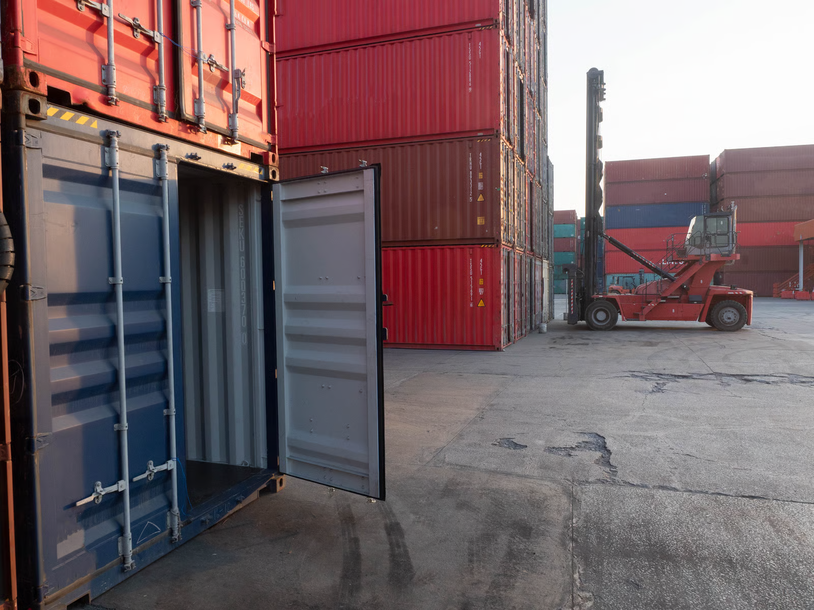 Loading cargo through the narrow end of a standard shipping container is one of the biggest frustrations in logistics. Forklifts struggle with long loads, workers waste time arranging items single-file, and oversized materials simply do not fit through a 7-foot-wide door. The open side container solves these problems by placing full-length doors along the long wall. In this guide, we cover what an open side container is, how the doors work, standard dimensions, real-world applications, pricing, and how it compares to other container types. Infinex can source open side containers for projects across Singapore in both new and used condition. What Is an Open Side Container? An open side container (also called a full-side access container, side-opening container, or side-door container) is a modified intermodal shipping container with bi-fold doors along one or both of its long walls instead of the conventional solid steel panels. While a standard container only has cargo doors on the short 8-foot wall, an open side container opens up the full 20-foot or 40-foot length of its side wall. This gives operators the ability to load, unload, and access cargo from the side rather than being restricted to end-loading only. The bi-fold doors are made from the same corrugated Corten steel as the rest of the container. When closed and sealed, the unit remains wind-tight and water-tight, just like a standard box. Structural integrity is maintained through a reinforced top rail, reinforced corner posts, and carefully engineered hinge systems. Open side containers are built to ISO standards and are compatible with standard container handling equipment. They are available in both 20ft and 40ft lengths, in standard height (8ft 6in) and high cube (9ft 6in) configurations. For a full breakdown of sizing, see our container sizes guide. https://app.envato.com/search/photos/0eb3cb14-fd6f-44ce-b3dc-915d3b4ac1ad?itemType=photos&term=Open+Side+Container&sort=relevance How Open Side Container Doors Work The door system is what sets the open side container apart. Understanding the mechanism, design variants, and opening options will help you choose the right configuration. Bi-Fold Door Mechanism Each door panel is made up of two hinged sections that fold against each other when opened, similar to a closet bi-fold door but built to industrial standards. The doors swing open between 180 and 270 degrees, and when fully opened, the panels fold flat against the adjacent wall or corner post, leaving the entire side opening completely clear. Each panel rides on heavy-duty hinges welded to vertical posts, designed to support 150 to 250 kg per panel while withstanding repeated opening and closing cycles. Doors can be opened individually or all at once, giving you flexibility for partial or full access. Door Configurations Full open-side (no centre post): Two large bi-fold assemblies meet in the middle. When opened, the entire wall is clear with no vertical obstruction. Best for very long or wide items. One-post/two-door: A single vertical centre post divides the side into two openings, each with its own bi-fold assembly. Adds structural rigidity while providing generous access. Four-door/three-post: Three vertical posts create four equal door sections. Highest structural strength, commonly chosen when stacking is required. Most open side containers also retain the standard end doors, giving you dual-access capability. Weatherproofing and Security Despite having an entire wall that opens, open side containers are engineered to be fully weather-tight when closed: Rubber gaskets: Continuous seals along every door edge, post junction, and threshold create a water-tight barrier Multi-point locking: Cam-action lock rods engage at the top, bottom, and middle of each door frame, with high-security padlock hasps Drainage channels: Door tracks and bottom rails direct water away from the interior Wind rating: Closed and locked units meet the same wind resistance standards as conventional containers, typically rated for sustained winds up to 150 km/h https://app.envato.com/search/photos/3e91e6b3-9ae2-4f67-a910-615e4992888f?itemType=photos&term=Open+Side+Container&sort=relevance Open Side Container Dimensions and Specifications Below are the standard dimensions for the most common open side container sizes. Exact measurements may vary slightly between manufacturers. 20ft Open Side Container (Standard and High Cube) Specification 20ft Standard 20ft High Cube External Dimensions (L x W x H) 6,058 x 2,438 x 2,591 mm 6,058 x 2,438 x 2,896 mm Internal Dimensions (L x W x H) 5,898 x 2,350 x 2,390 mm 5,898 x 2,350 x 2,690 mm Side Door Opening (W x H) 5,758 x 2,280 mm 5,758 x 2,585 mm End Door Opening (W x H) 2,340 x 2,280 mm 2,340 x 2,585 mm Tare Weight 2,550 to 2,800 kg 2,750 to 3,050 kg Maximum Payload 21,500 to 24,000 kg 21,000 to 24,000 kg Cubic Capacity 33.0 to 33.2 cbm 37.2 to 37.5 cbm 40ft Open Side Container (Standard and High Cube) Specification 40ft Standard 40ft High Cube External Dimensions (L x W x H) 12,192 x 2,438 x 2,591 mm 12,192 x 2,438 x 2,896 mm Internal Dimensions (L x W x H) 12,032 x 2,350 x 2,390 mm 12,032 x 2,350 x 2,690 mm Side Door Opening (W x H) 11,832 x 2,280 mm 11,832 x 2,585 mm End Door Opening (W x H) 2,340 x 2,280 mm 2,340 x 2,585 mm Tare Weight 4,200 to 4,800 kg 4,500 to 5,200 kg Maximum Payload 26,000 to 28,000 kg 26,000 to 28,500 kg Cubic Capacity 67.3 to 67.7 cbm 75.8 to 76.3 cbm Construction and Materials Open side containers use the same industrial-grade materials as standard shipping containers, with additional reinforcement to compensate for the opening side wall. Corten steel (weathering steel): Walls, roof, floor frame, and door panels are fabricated from Corten steel, which forms a protective rust layer that shields the underlying metal from corrosion. Ideal for containers exposed to rain, salt spray, and tropical humidity. Reinforced frame: The top side rail, corner posts, and bottom side rail are all reinforced with heavier gauge steel sections to maintain load-bearing capacity after removing the solid wall. Marine-grade plywood flooring: 28 mm thick, treated with insecticide and fungicide, rated to support forklift traffic and heavy point loads. Forklift pockets: Standard ISO-spaced pockets built into the base for lifting and repositioning. Heavy-duty hardware: Forged steel hinges designed for tens of thousands of cycles. All lock rods, handles, and cam keepers are zinc-plated or galvanised. Multi-layer coating: Zinc-rich primer, intermediate epoxy coat, and marine-grade polyurethane topcoat for long-term corrosion protection. Advantages of Open Side Containers Full forklift access from the side. A forklift can approach perpendicular to the container and place pallets anywhere inside without driving through a narrow 8-foot corridor. Faster loading and unloading. Multiple workers or machines can operate along the open side simultaneously. Side-loading can reduce handling time by 30% to 50% compared to end-loading. Oversized cargo capability. Items wider than the 7 ft 8 in end door can be loaded through the side opening, which stretches up to 38 ft 10 in on a 40ft unit. Reduced cargo damage. Items can be placed directly into position rather than being dragged or tilted through a narrow door. Easy access to all cargo. Every item is immediately reachable from the side, making inventory management and partial unloading far more practical. Outstanding conversion potential. The full-length opening is perfect for large windows, folding walls, serving hatches, or roll-up shutters, making these containers ideal for customised solutions. Storefront and display capability. When opened, the container creates a natural covered shopfront. The roof provides shade and rain protection while the full interior is visible. Weather-tight when closed. Rubber gaskets and multi-point locks ensure the container is fully sealed, meeting the same standards as conventional containers. Strong resale value. Limited supply and strong demand mean open side containers hold their value well. https://app.envato.com/search/photos/1325f9a0-18cb-4bc5-bef3-f56045e3edf1?itemType=photos&term=Open+Side+Container&sort=relevance Disadvantages of Open Side Containers Higher purchase cost. Open side containers cost approximately 1.5 to 2 times more than a comparable standard container due to complex door engineering and reinforced framing. Heavier tare weight. The reinforced frame and bi-fold doors add 200 to 500 kg, slightly reducing maximum payload capacity. Limited availability. These are a specialty product with limited production volumes. Lead times for new orders are typically 8 to 14 weeks. Used open side containers are particularly scarce. Lateral clearance required. The bi-fold doors need 600 to 800 mm of clearance to swing open, which can be a constraint in tight spaces. Reduced stacking capacity. Most are rated for 3 to 5 high stacking when empty, compared to 6 to 9 for standard containers. Always check the CSC plate. Door maintenance. Hinges, lock rods, and gaskets require periodic lubrication and inspection, especially in coastal or tropical environments. Open Side Container Uses and Applications Construction sites. Side-loading allows teams to store and access timber, steel beams, pipes, scaffolding, and heavy equipment without tight end-door manoeuvring. Multiple trades can access different sections simultaneously. Browse our range of products suitable for construction. Warehousing and distribution. Open side containers serve as flexible overflow storage during peak seasons. Side access makes pick-and-pack operations faster and enables proper first-in, first-out inventory rotation. Retail pop-up shops and events. When opened, the container transforms into a sheltered, branded retail or food-service space. Lockable when closed for overnight security. Ideal for markets, festivals, product launches, and trade shows. Agriculture. The side access is useful for loading large hay bales with a tractor-mounted loader or storing equipment too wide for standard doors. Military and emergency services. Side-loading enables rapid deployment and distribution of supplies, equipment, and field infrastructure in time-sensitive operations. Modular conversions. The pre-engineered full-length opening saves significant fabrication costs compared to cutting and reinforcing a standard container wall. Architects use these for offices, studios, cafes, garages, and modular homes. Explore Infinex customised container solutions for conversion options. Open Side Container vs Other Container Types Feature Open Side Standard Double-Door (Tunnel) Curtain-Sided Open Top Side wall access Full-length bi-fold doors Fixed steel panel Fixed steel panel PVC/canvas curtains Fixed steel panel End doors Standard double doors Standard double doors Double doors on both ends Standard double doors Standard double doors Loading direction Side and end End only Both ends Side and end Top and end Max opening width (40ft) Up to 38 ft 10 in 7 ft 8 in 7 ft 8 in (each end) Full side length 7 ft 8 in Security level High (steel doors, multi-point locks) High High Low (curtains can be cut) Medium (tarpaulin roof) Weather tightness Full (gaskets and locks) Full Full Partial Partial Stacking capacity 3 to 5 high 6 to 9 high 5 to 7 high 2 to 3 high 4 to 6 high Tare weight (20ft) 2,550 to 2,800 kg 2,200 to 2,350 kg 2,400 to 2,600 kg 2,300 to 2,500 kg 2,300 to 2,500 kg Price (20ft new) $6,500 to $9,500 $3,000 to $5,000 $4,000 to $6,500 $5,000 to $7,500 $4,500 to $7,000 Availability Limited Widely available Moderate Limited Moderate Best for Side access, oversized cargo, conversions General cargo, shipping Drive-through access Fast roadside loading Top-loading with crane Open Side Container Pricing Open side container prices depend on size, condition, door configuration, and market availability. Below is a guide to current pricing in the Singapore and Southeast Asian market. Condition 20ft Price (USD) 40ft Price (USD) New (one-trip) $6,500 to $9,500 $9,500 to $15,000 Refurbished $5,000 to $7,000 $7,500 to $11,000 Used (good condition) $4,000 to $6,000 $6,000 to $9,000 40ft high cube open side containers sit at the upper end of these ranges due to additional material and higher demand. Used open side containers are significantly harder to find than used standard containers. When available, check the condition of doors, gaskets, hinges, and locking mechanisms carefully, as these components experience the most wear. Check our used container inventory for current availability. Why Open Side Containers Cost More The higher price reflects complex bi-fold door engineering, heavier structural reinforcement, specialised hardware components, lower production volumes, and additional quality control testing for door alignment and gasket sealing. For container accessories such as additional locks, shelving, or lighting to complement your open side container, visit our accessories page. https://app.envato.com/search/photos/5a67a99c-d148-4bdd-a4c8-2672d08942e6?itemType=photos&term=Open+Side+Container&sort=relevance Frequently Asked Questions 1. What is an open side container used for? An open side container is used for any application that benefits from full-length side access, including construction site storage, warehousing, retail pop-up shops, agricultural storage, military logistics, and modular building conversions. 2. Can an open side container be shipped by sea? Yes. Open side containers are built to ISO standards and can be shipped on container vessels, trailer chassis, and rail. Ensure the doors are properly secured and sealed according to carrier requirements. 3. Are open side containers waterproof? Yes. When all doors are closed and locked, the rubber gaskets and multi-point locking system create a weather-tight seal meeting the same standards as conventional shipping containers. 4. Can I stack open side containers? Yes, but with reduced capacity. Most are rated for 3 to 5 high stacking when empty. Always check the CSC plate on the specific unit for its approved stacking weight. 5. Can the side doors be removed? Yes. The bi-fold doors are mounted on bolt-on hinges and can be removed if a permanent full-side opening is desired. This is commonly done for conversion projects. 6. Do open side containers have end doors too? Most open side containers retain the standard double doors on the short end wall, giving you dual-access capability. Side-only models (no end doors) are less common. 7. Can I convert an open side container into a shop or office? Absolutely. Open side containers are among the most popular choices for container conversions. The full-length opening provides a ready-made shopfront, display area, or large window opening. Infinex offers customised container solutions for fit-outs of all types. 8. How quickly can I get an open side container in Singapore? New one-trip containers typically have lead times of 8 to 14 weeks. In-stock units can often be delivered within 3 to 7 business days. Contact Infinex for availability and pricing through our services page or contact us directly to discuss your requirements.